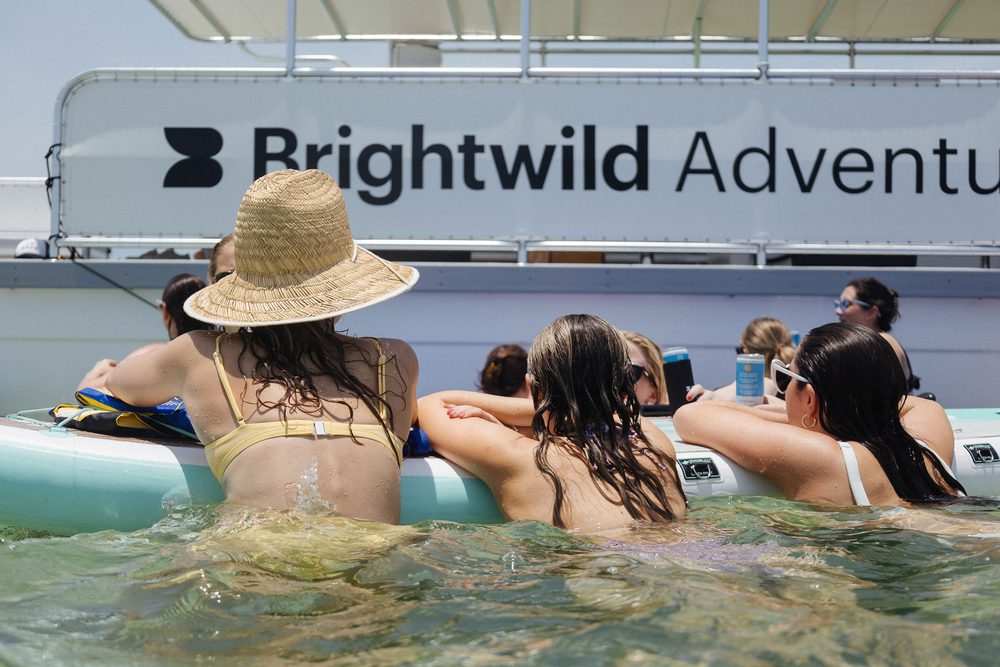 Guests in the water beside the Brightwild Adventures boat at the sandbar