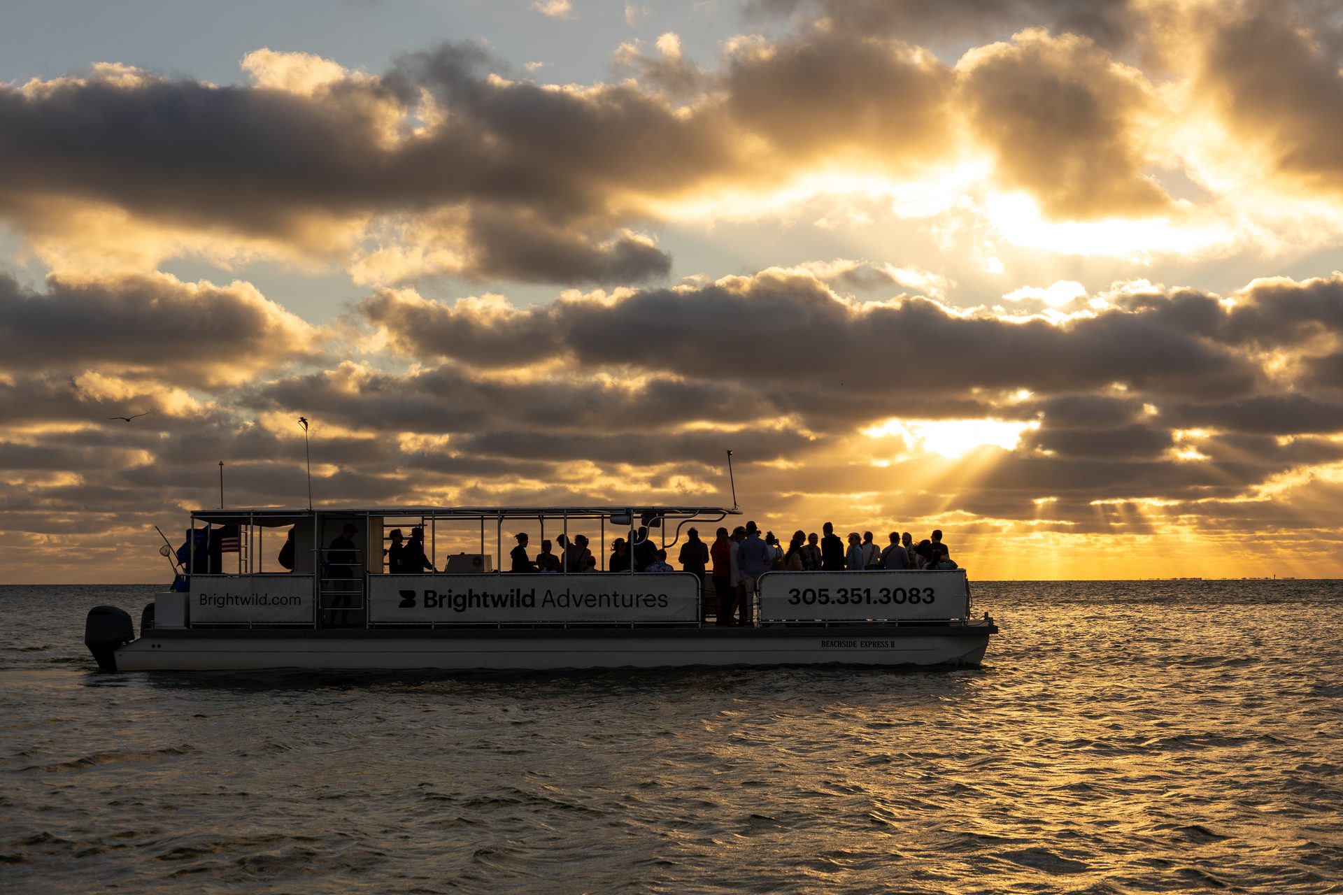 The boat full of guests under an orange Key West sunset